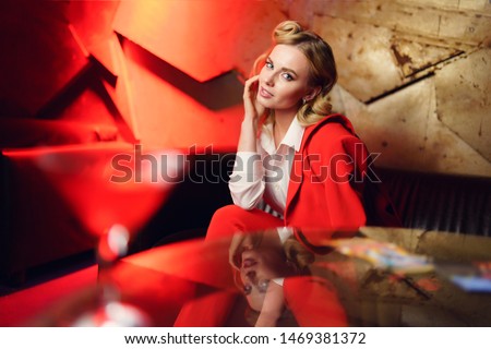 Photo of young blonde sitting on leather sofa near table
