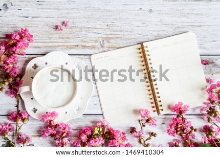 Morning coffee mug for breakfast, notebook, pen, pink flowers on white wooden table, top view, flat lay style. Woman working desk. Mockup, overhead