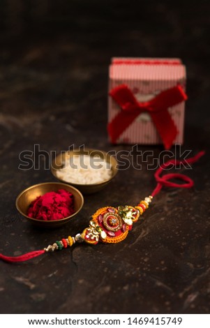 Raksha Bandhan background with an elegant Rakhi, Rice Grains, Kumkum  and gift box. A traditional Indian wrist band which is a symbol of love between Brothers and Sisters.