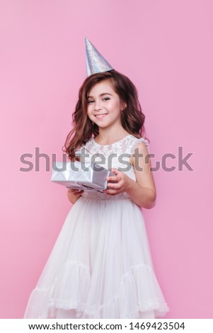 smiling child girl with gift box on birthday party on pink background