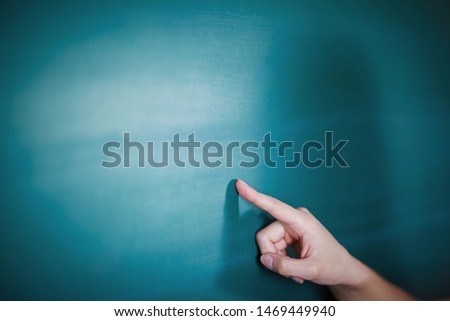 Girl shows on empty copy space on the school board. Education concept. Close-up. Hand in frame.