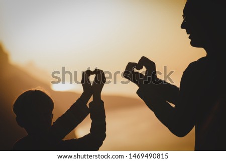 father and son enjoy sunset nature, making hearts with hands