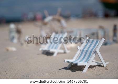 Sand and shells, sea sailing symbols, fish cutter in bokeh background, blue sky.
