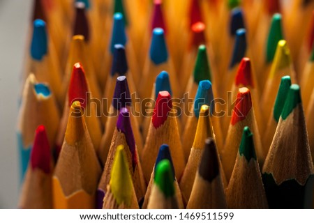 Close-up top of colored sharpened pencils standing next to each other on the table of an artist or a child. The concept of drawing and creativity