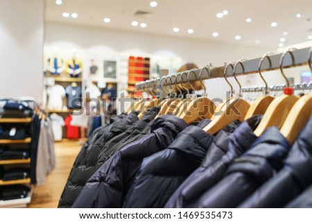 Modern show room selling clothes men, women children. Hangers bright fashionable clothes. Trousers, sweater  hoodie on a hanger in a fashion store for youth. Soft focus, bokeh. Sell-out. Style.