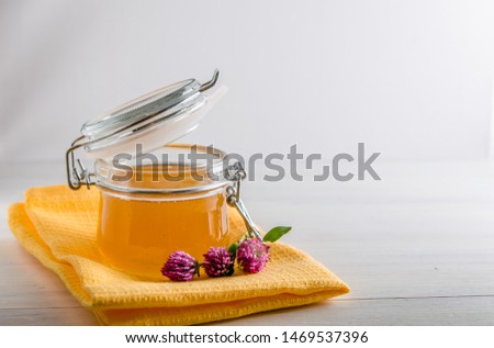 fresh honey in a jar and flowers clover on a white background with a copy space