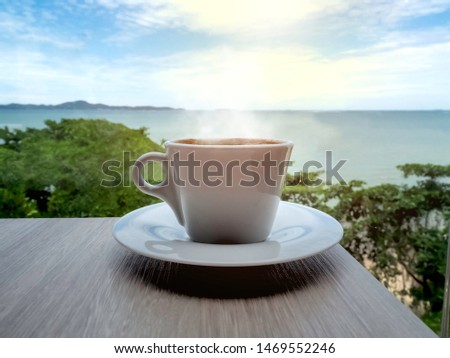 Close up a cup of black coffee on wood table and sea-view background in the late morning of vacation time.