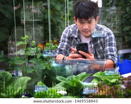 young smart Asia Farmer using Ar,Vr,3d projection glass Technology at his smart farm.
