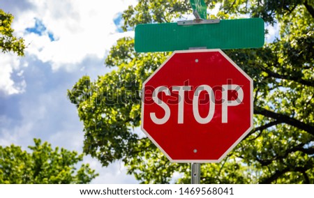 Stop road sign on an intersection. Blur trees and blue sky background. Sunny spring day in California