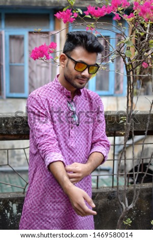 Portrait of a young and handsome man standing in front of a vintage house wearing a traditional purple kurta pyjama. Indian lifestyle and fashion.