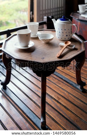 Porcelain tea set on a wooden table. Picture with grain and color from film simulation filter.
