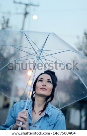 Happy young woman walking with umbrella under the rain stock photo