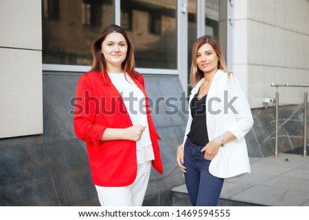 Two businesswomen hold a meeting near the office building. Business partnership, negotiations, profitable contract.