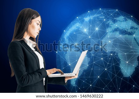 Attractive youong caucasian businesswoman using laptop with glowing polygonal globe on dark background. AI and data concept