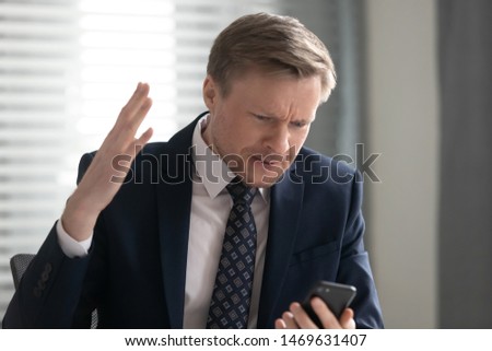 Angry businessman in suit get mad using cellphone experience virus attack or spam with data loss, furious male employee feel annoyed having software problems with smartphone, gadget breakdown Royalty-Free Stock Photo #1469631407