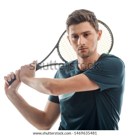 Man with a racket behind head. Handsome tennis player doing a big swing to make a strong shot.