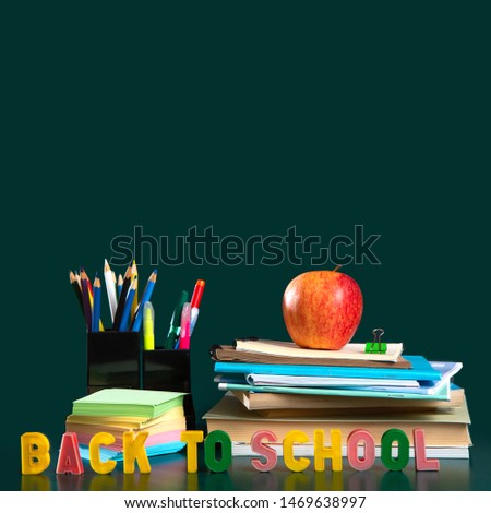 Inscription BACK TO SCHOOL. Still life with school supplies. Green background. Notebooks, notebooks, felt-tip pens, colored pencils, an apple. Colorful picture. Copy space