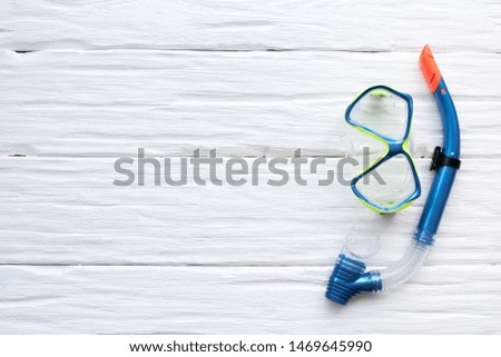 Underwater mask and snorkel over white wooden table background with a copy space.