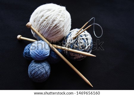 Woolen yarn for knitting. Close-up shots of white and blue balls of natural wool yarn and wooden knitting needles