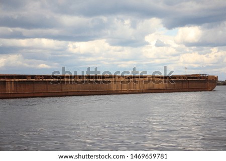 Empty barge on the river close-up, water transportation of bulk materials on river on stormy sky background
