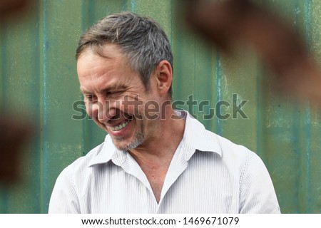 Artistic portrait of an elderly man of European appearance on the background of an iron sea container