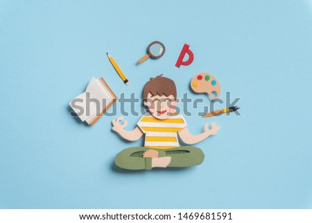 Little pupil sitting in lotus pose and meditating. Book, pencil, magnifier, protractor, palette of watercolors, paint brush around schoolchild. Back to school concept. Hand cut illustration from paper