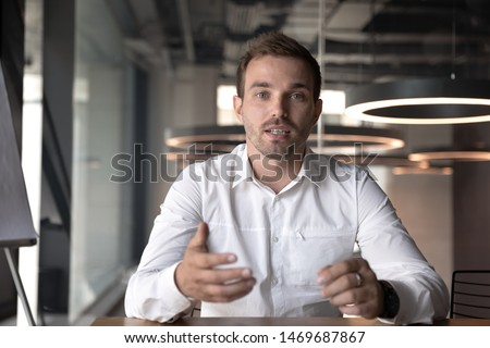 Businessman making video call, looking at camera and talking, discussing strategy with partners online, millennial business coach mentor recording webinar, hr manager holding distance job interview Royalty-Free Stock Photo #1469687867