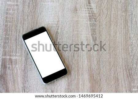 Mock up image of mobile smart phone with black white screen on wooden table background. Using technology concept.