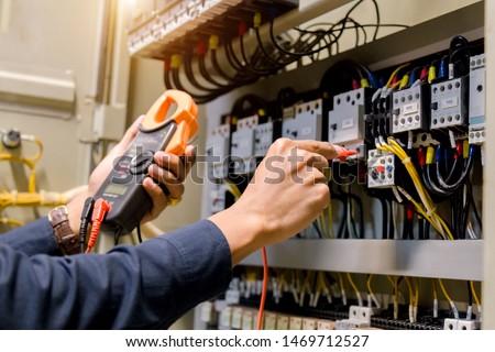 Electrician engineer work  tester measuring  voltage and current of power electric line in electical cabinet control. Royalty-Free Stock Photo #1469712527