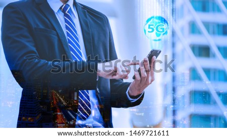 5G internet network communication concept with double exposure of Young businessman standing and point to phone and 5G global hologram with cityscape background.