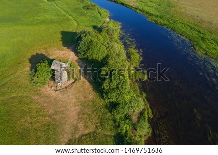  Old wooden mill on the banks of the Sorot River on a sunny June morning (aerial photo). Mikhailovskoe, Pushkin Mountains. Russia