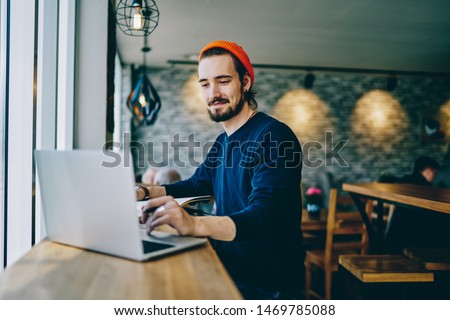 Positive caucasian male checking news from networks working remotely on publicity area, man freelancer reading information on web page looking on screen of laptop computer connected to wifi internet Royalty-Free Stock Photo #1469785088