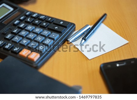 Book, pen, a cup of coffee, smart phone and small calculator on wooden background