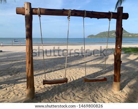 Swing on a Summer holidays sandy beach with ocean and island in the background