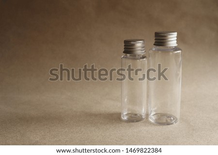 Model image of a clear glass bottle with a metal cover on a brown background,mockup