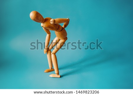 Concept of back pain. A wooden figure depicts a pain in the back. Royalty-Free Stock Photo #1469823206
