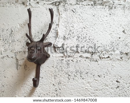 Hanging a deer-shaped iron on a brick wall, white paint