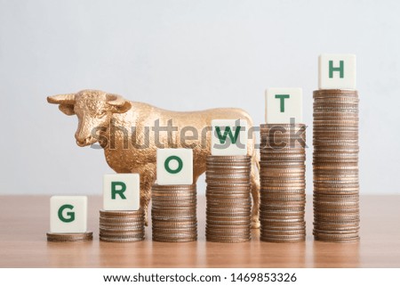 Business and finance growth concept. Green word GROWTH on stack step coins as graph rising up with golden bull. Bull market in stock market or success performance or achieve KPI target plan