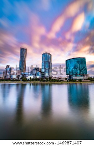 Beautiful wide angle long exposure cityscape of Yekaterinburg city, Russia at sunset with blurred blue and purple clouds. Skyscrapers reflecting in water of Iset river
