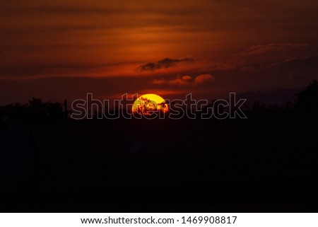 Natural Sunset Sunrise Over Field Or Meadow. Bright Dramatic Sky And Dark Ground. Countryside Landscape Under Scenic Colorful Sky At Sunset Dawn Sunrise. Sun Over Skyline, Horizon. Warm Colours.