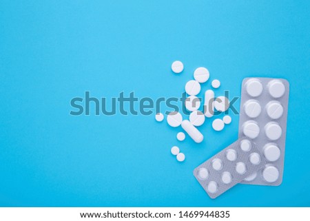 White pills on blue background with copy space, top view