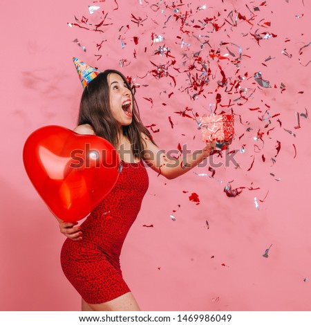 The girl is happy with the gift and confetti. Pink background