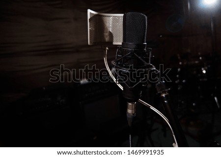 Close up studio condenser microphone with pop filter and anti-vibration mount live recording with black background. Side view