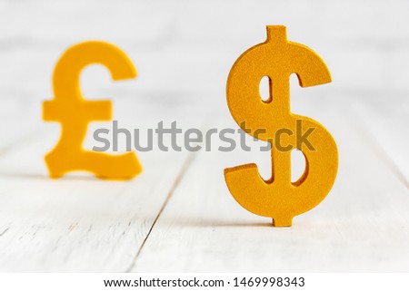 Dollar sign over pound sign on white wood table over white brick background with copy space.