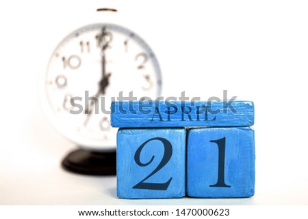 april 21st. Day 20 of month, handmade wood cube calendar and alarm clock on blue color. spring month, day of the year concept.