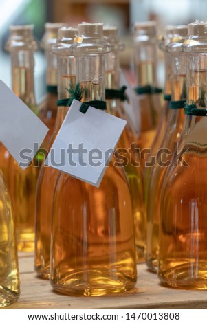 Yellow bottles background. Close-up of a set glass bottles with yellow transparent liquid and empty paper tag on a wooden table. Selective focus.  Concept Fathers day or other holidays.