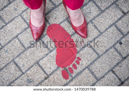 Female feet with footprint painted on the asphalt