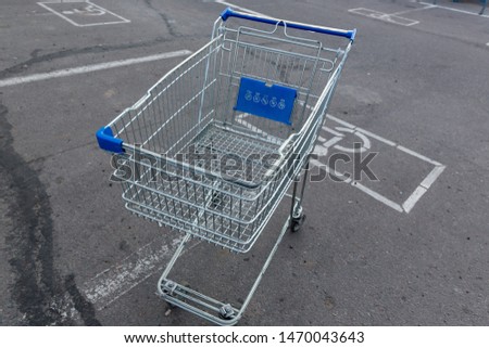A metal trolley with blue plastic elements stands on the asphalt car Park for the disabled.
