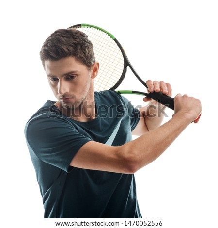 Portrait of a young man playing tennis on white. Player swings a racket across the body, looks down and thinks about further moves.