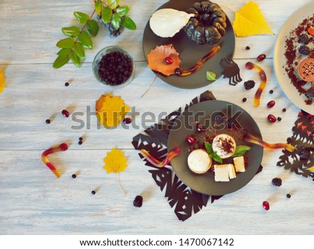 Halloween treat, autumn leaves and dessert with chocolate, ice cream and jelly worms on a wooden table